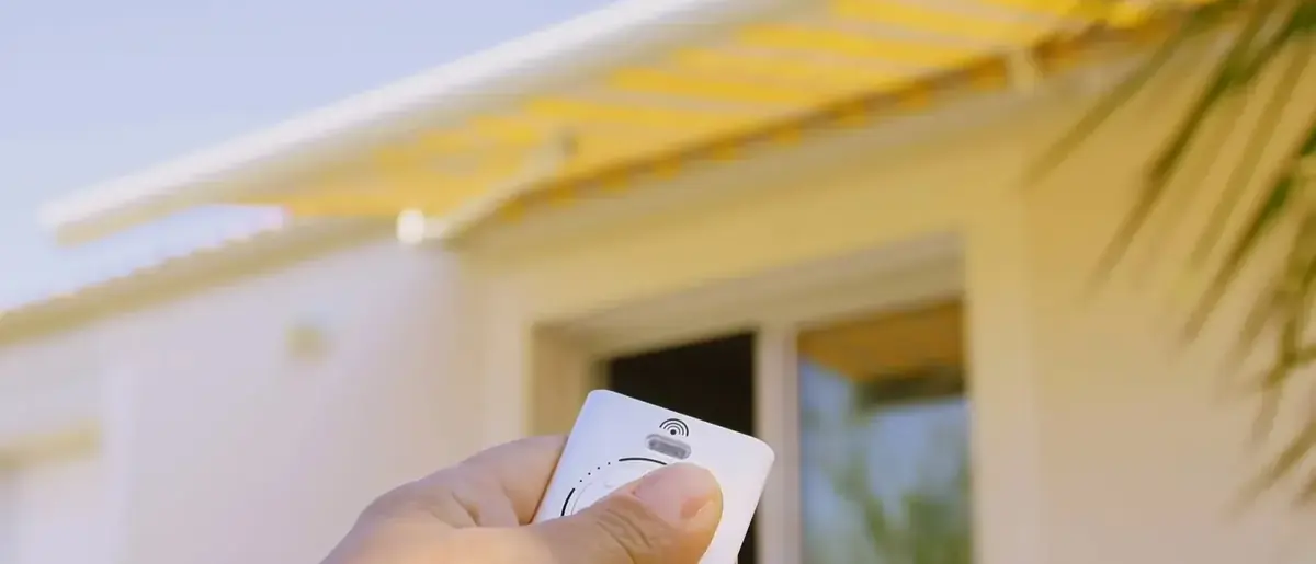 Télécommande de volet roulant tenue devant une façade
